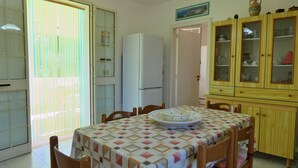 A dining area with a table set for four, a refrigerator, and a wooden cabinet with glass doors.