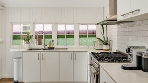 Una cocina moderna con armarios blancos, una estufa a gas y una ventana con vistas al verdor.