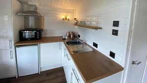 Une cuisine de taille réduite avec des meubles blancs, un four à micro-ondes, un grille-pain et un évier.
