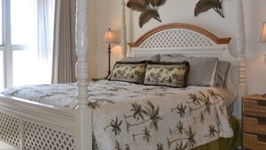 Ein Himmelsbett mit Baldachin, Deckenventilator und Wandbildern.