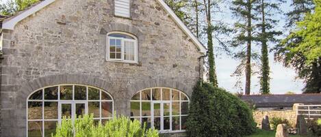 Un edificio de piedra con dos ventanas de arco y un pequeño ventanuera.