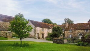 A stone building with a grassy lawn and a tree in front.