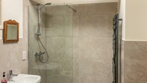 A bathroom with a shower, sink, and a mirror.
