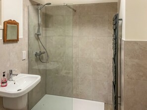 Un baño con ducha, lavamanos y espejo.