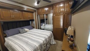 Ein Schlafzimmer mit zwei Betten, Holzschränken, einem Deckenventilator und einem Nachttisch mit Lampe.