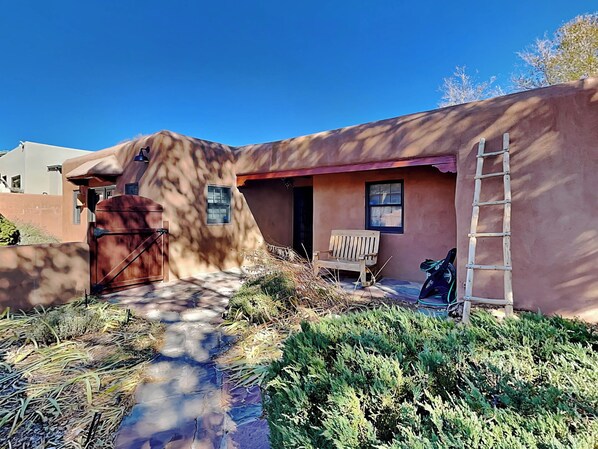 A rustic building with a wooden bench and a ladder outside. - Casa Calabaza by Kokopelli Property Management (Santa Fe)