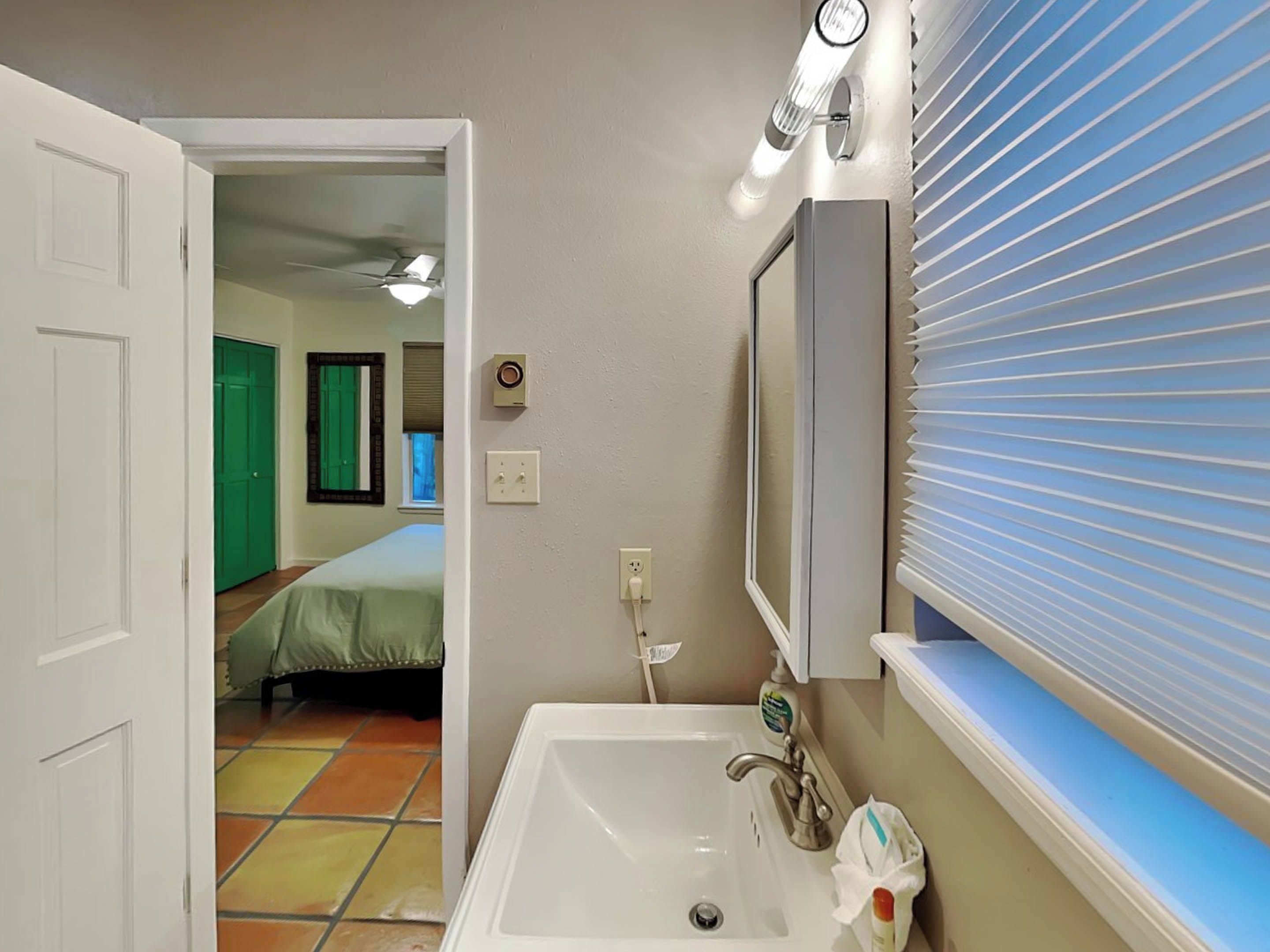 Ein Badezimmer mit Waschbecken, Spiegel und Fensterläden.