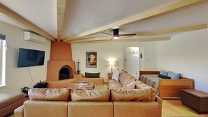 Un ampio soggiorno con un grande divano in pelle, un camino, una televisione e una ventola a soffitto.
