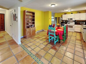 A kitchen with white cabinets, a red table, and a tiled floor. - Casa Calabaza by Kokopelli Property Management (Santa Fe)