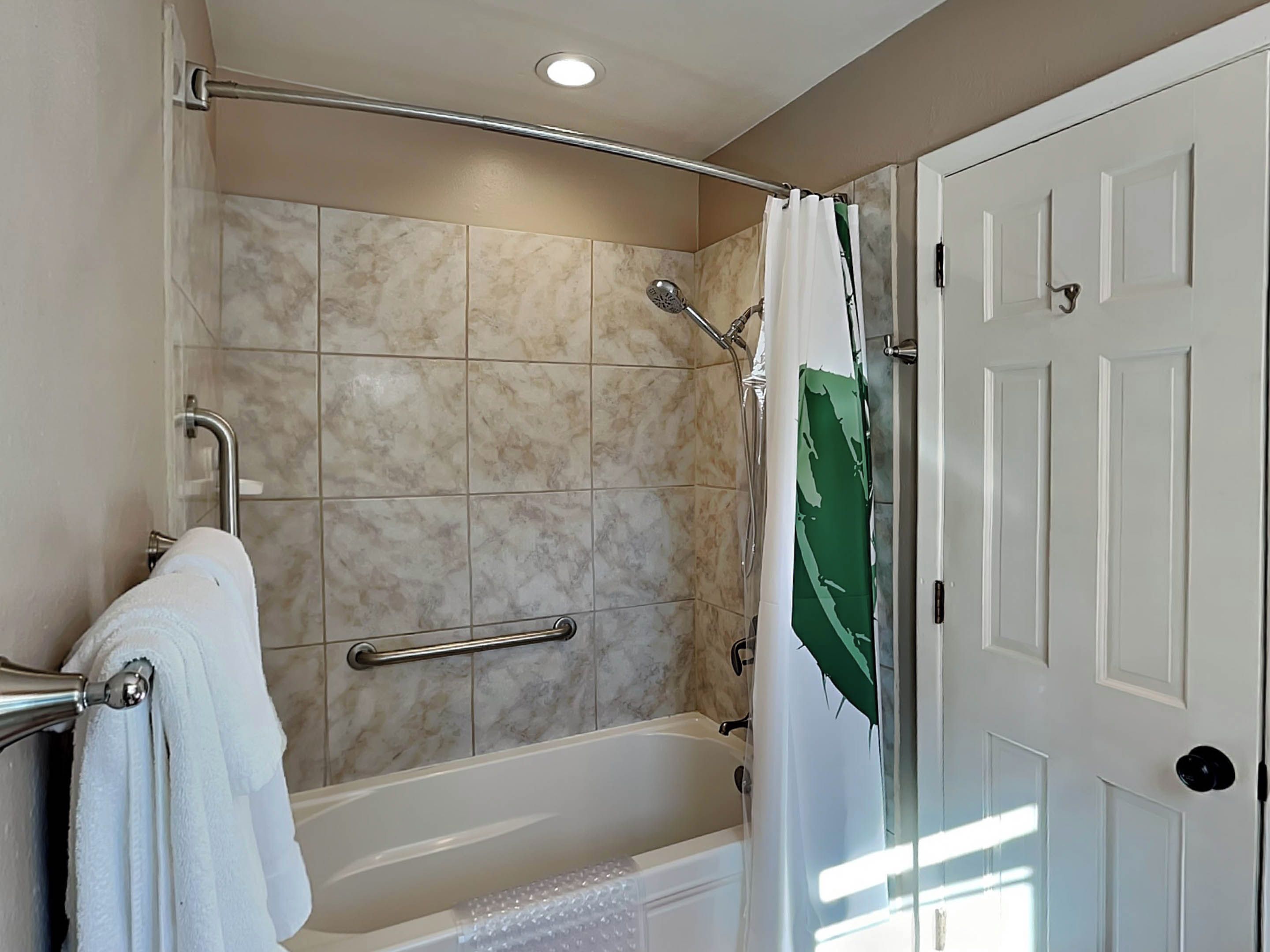 A bathroom with a bathtub, shower, and a door.