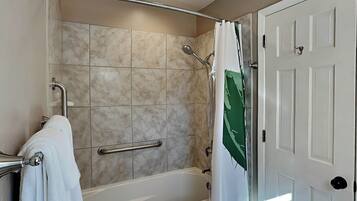 A bathroom with a bathtub, shower, and a door.