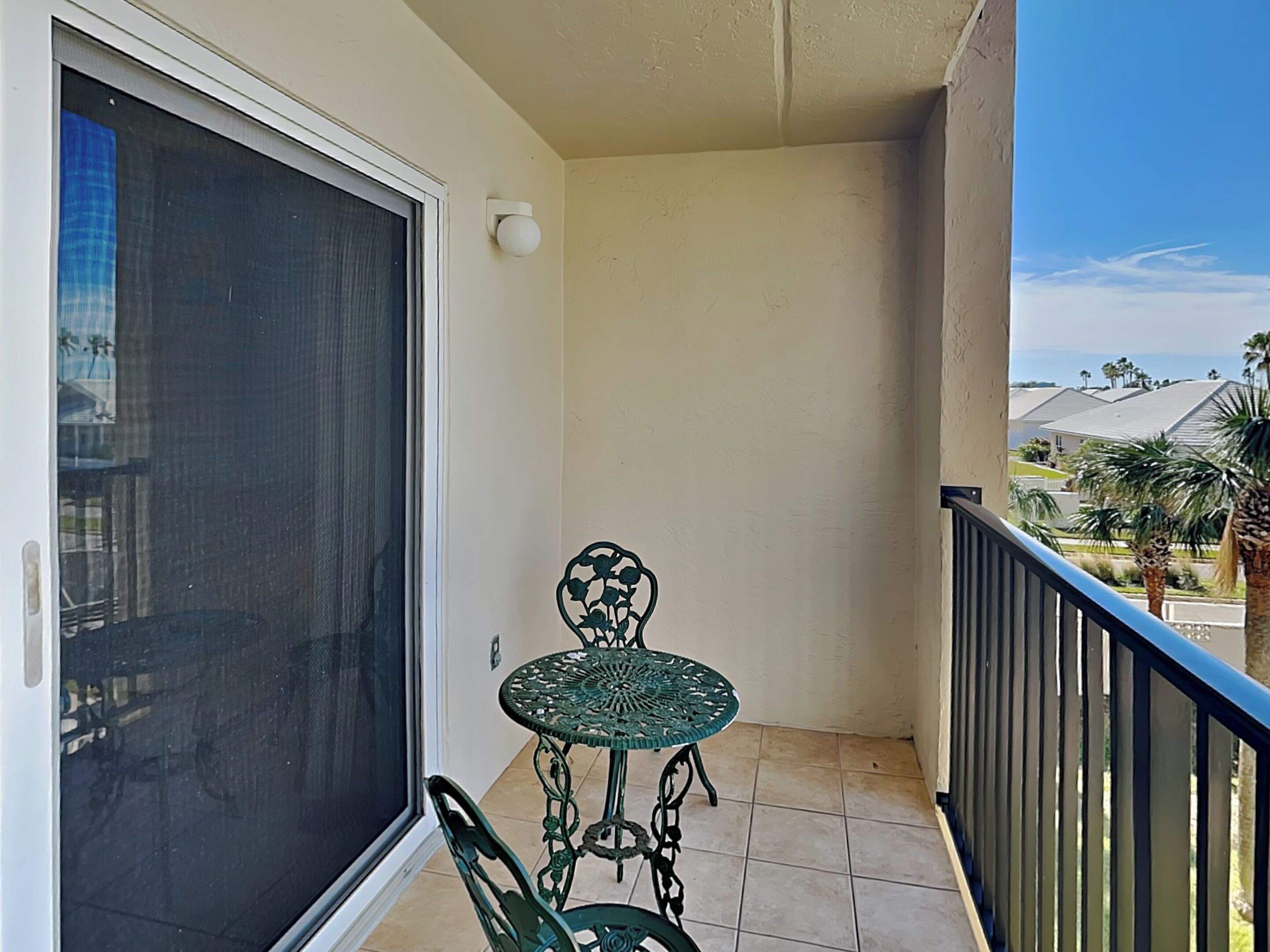 A balcony with a sliding glass door, a small round table, and a chair.