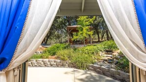 A covered patio with a pergola, stone pathway, and lush greenery. - Cody's Comfy Cabin-Near Yosemite (Mariposa)