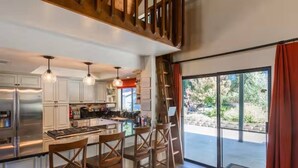 A modern kitchen with a central island, stainless steel appliances, and wooden chairs. - Cody's Comfy Cabin-Near Yosemite (Mariposa)