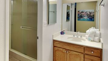 A bathroom with a glass shower door, a wooden vanity with a sink, and a mirror.