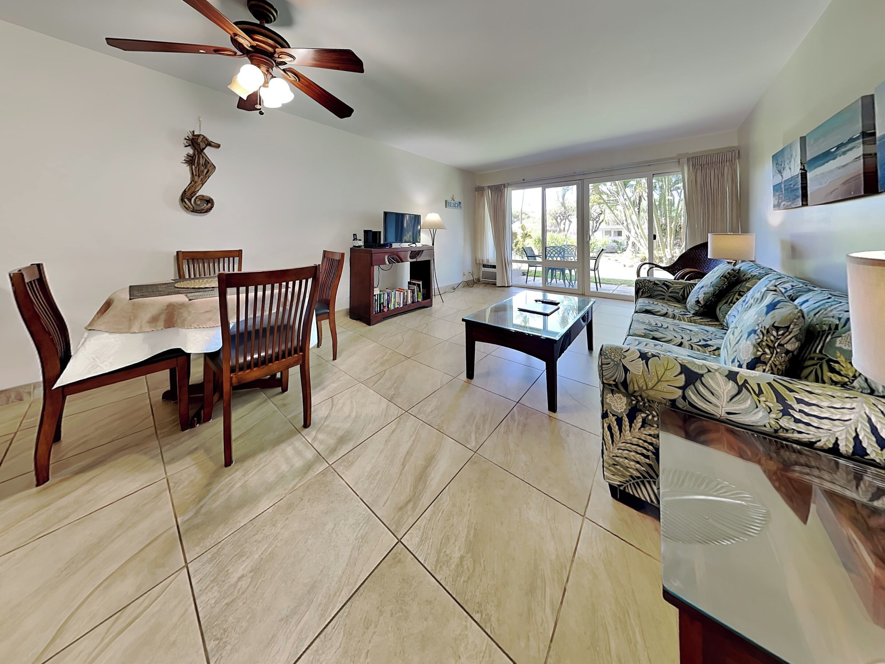 A spacious living room with a dining area, a sofa, a coffee table, and a ceiling fan.