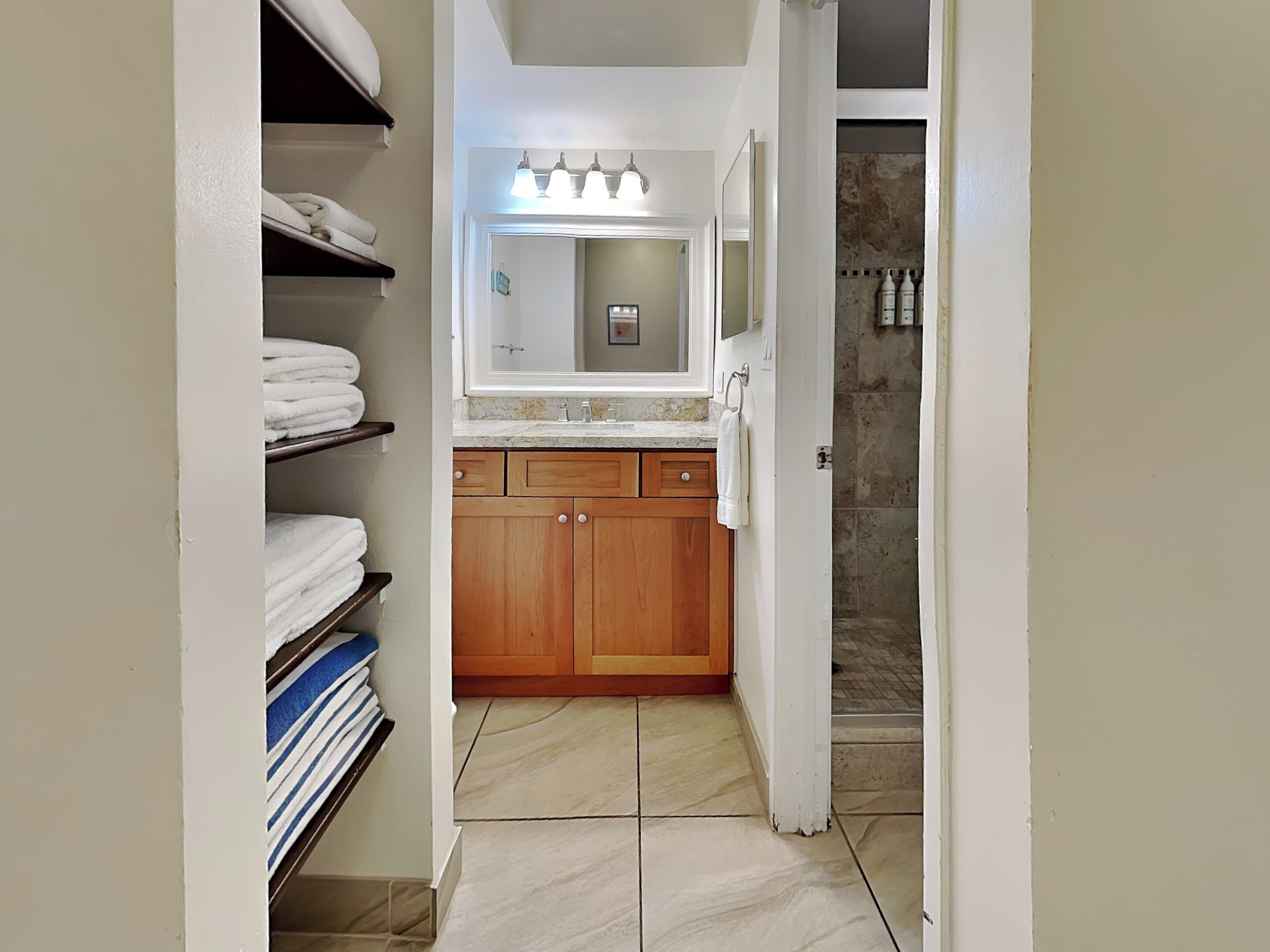 A bathroom with a vanity, a mirror, and a shower area.