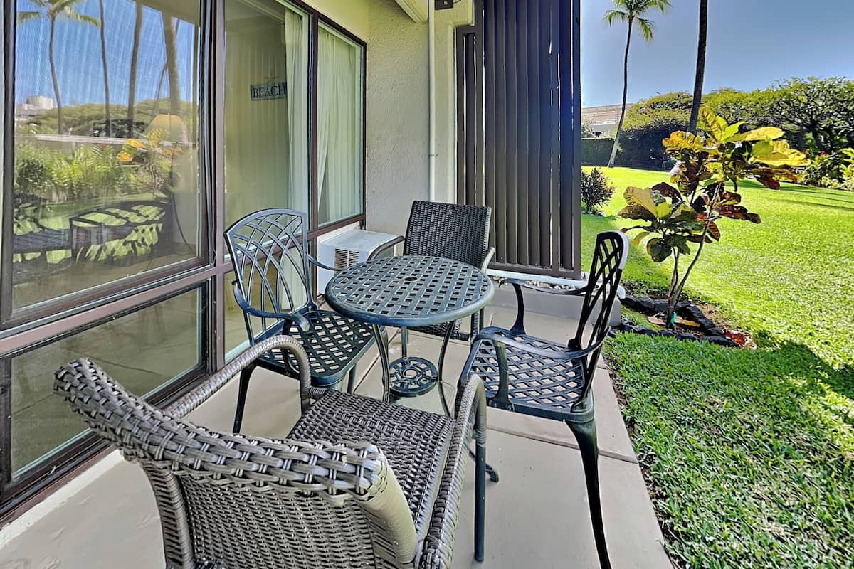 A patio with wicker furniture and a view of a golf course.