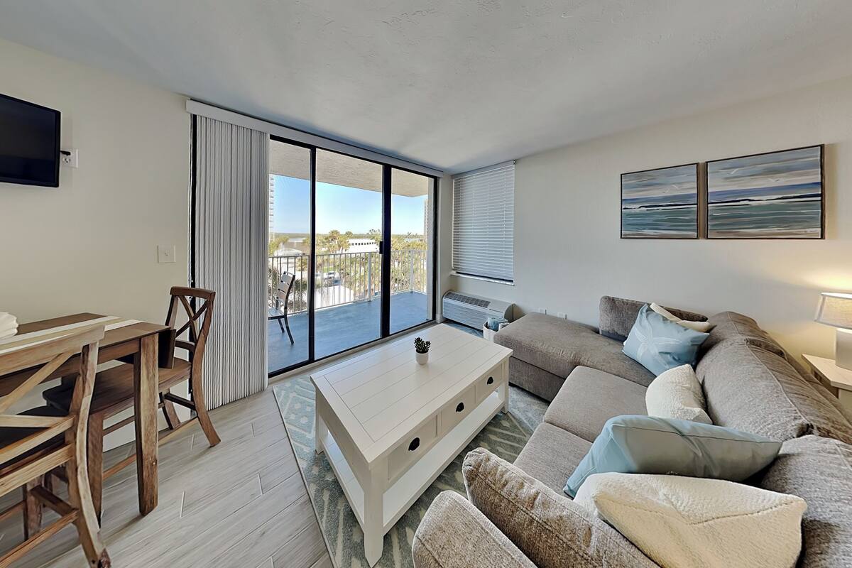 Ein modernes Wohnzimmer mit einer Couch, einem Couchtisch, einem Fernseher und einem Balkon mit Blick.