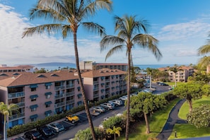 A multi-story hotel with balconies, a parking lot, and a view of the ocean. - Maui Vista 3402 by Maui Rental Group (Kihei)
