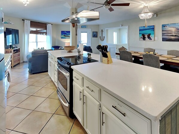 A spacious kitchen with white cabinetry, a large island, and a dining area with a table and chairs.