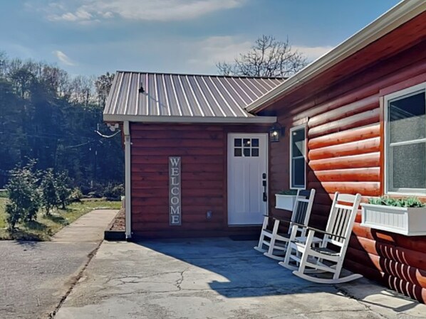 A wooden cabin with a 'WELCOME' sign, a porch with rocking chairs, and a metal roof. - Swinging S'mores by Jackson Mountain Rentals (Sevierville)