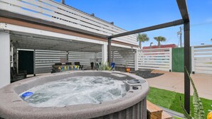 Un bain à remous situé dans un espace extérieur abrité, avec une terrasse et des sièges.