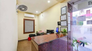 A reception area with a marble counter, a fan, a window with blinds, and framed certificates on the wall.