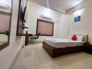 A hotel room with a bed, a desk, a chair, a television, and a window with blinds. - Triple Tree Hotels and Resorts (Bhubaneshwar)