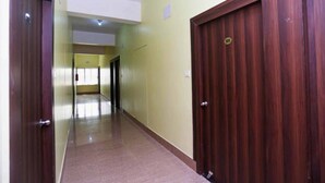 A hallway with wooden doors, a yellow wall, and a tiled floor.