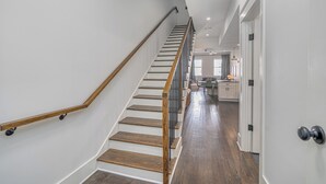 Eine Treppe mit Holzdielen und Metallgeländer, die zu einem Küchenbereich mit Schränken und einer Arbeitsplatte führt.