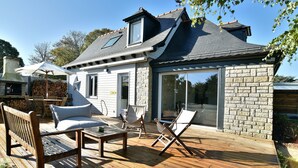 Une maison dotée d’une terrasse, d’une façade en pierre et d’une grande porte-fenêtre coulissante.