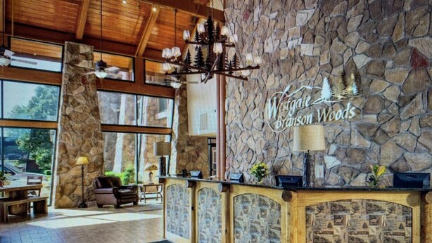 Un área de recepción con pared de piedra, un candelabro y un letrero que dice "Viney Branson Woods".