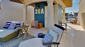 A covered outdoor seating area with a blue door marked "30A", wicker furniture, and a patterned rug. - Coastal Grove by Southern Vacation Rentals (Santa Rosa Beach)