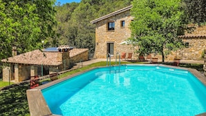 A stone building with a swimming pool, surrounded by trees and a small patio area. - Majordoms Molí - La Garrotxa (Beuda)