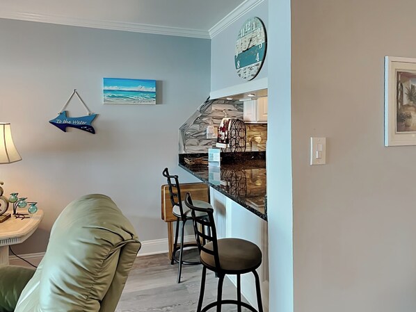 Une cuisine moderne avec un pare-feu en pierre, des tabourets de bar et un luminaire suspendu.