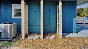 A house with a blue exterior, a white window, and a covered outdoor area with a gravel path. - PC Beach Retreat B by Resort Collection (Panama City Beach)