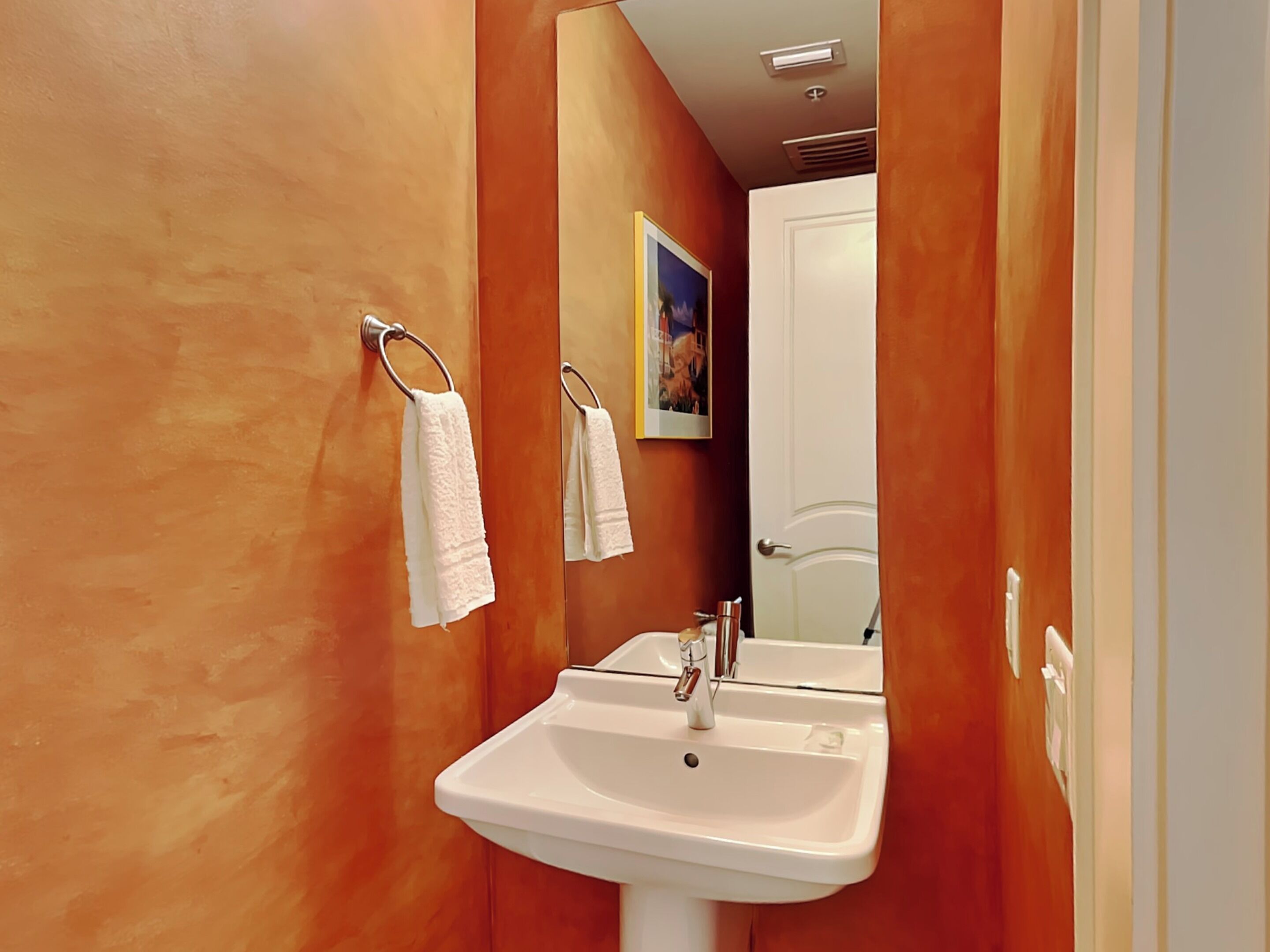Un baño con un lavamanos blanco, dos toalleros y un espejo.