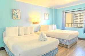 A hotel room with two beds, a window with a view of a building, and two wall-mounted lamps.