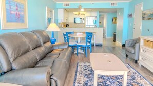 A living room with a sofa, a coffee table, and a dining area with chairs. - Sand Dunes 1246 (Myrtle Beach)