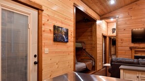 Interior d'una cabana de fusta amb un sofà, una televisió i un quadre d'una escena forestal.
