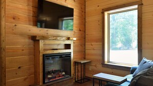 Interior d'una cabana de fusta amb una llar de foc, una finestra i un sofà.