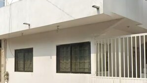 Un bâtiment moderne à deux étages, doté d’un toit plat, de murs extérieurs blancs et d’une entrée sécurisée par un portail.