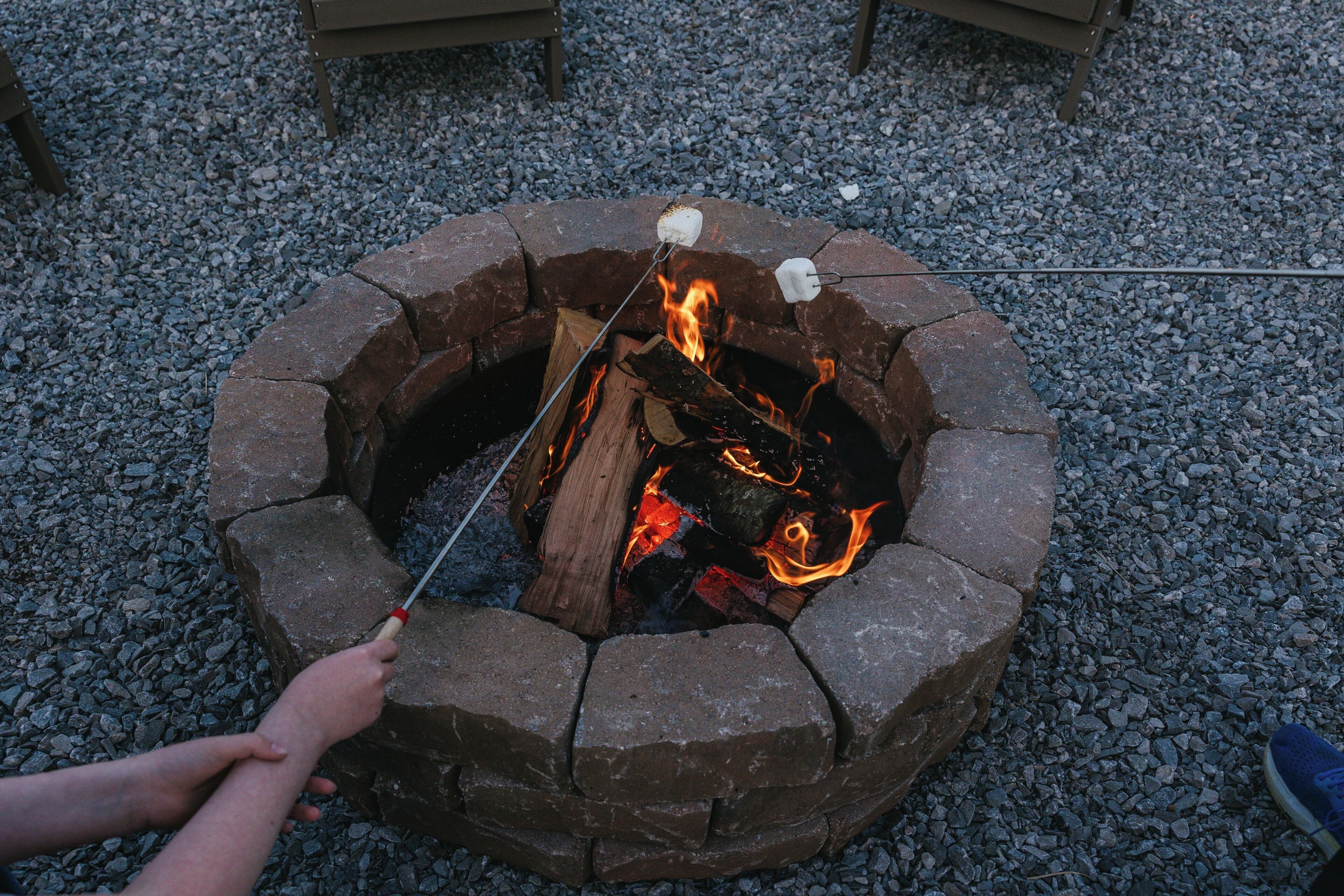 A stone fire pit with logs and a stick for roasting marshmallows.