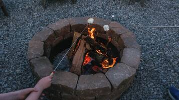 A stone fire pit with logs and a stick for roasting marshmallows.