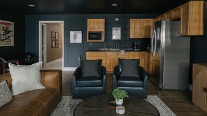A modern living room with a brown leather sofa, two black leather chairs, a round coffee table with a plant, and wooden cabinets in the background. - Backroads and Barrels Bourbon Trail Retreat (Salvisa)