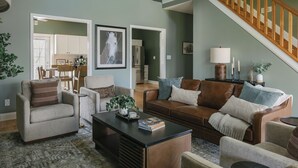 A living room with a sofa, armchairs, a coffee table, and a staircase. - Backroads and Barrels Bourbon Trail Retreat (Salvisa)