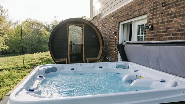 A hot tub in a backyard with a brick house in the background. - Backroads and Barrels Bourbon Trail Retreat (Salvisa)