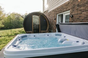 Un bain à remous dans un jardin, avec une maison en briques en arrière-plan.