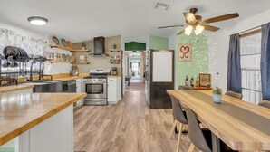 Une cuisine moderne dotée d’un îlot central, d’un coin repas avec une longue table et d’un ventilateur de plafond.